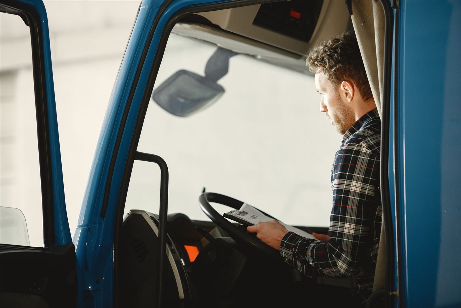 Lorry driver reading paperwork in the cab